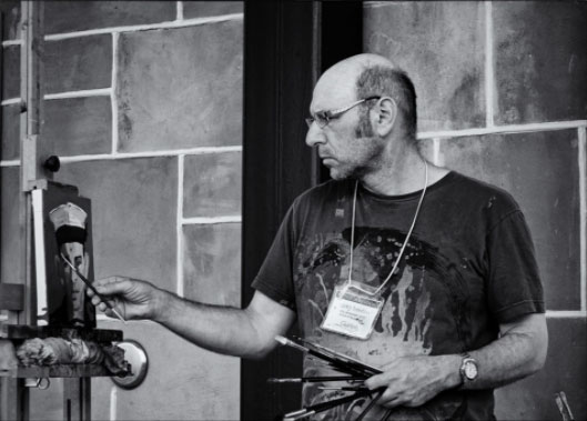 Black and white photo of Greg Denton painting a portrait