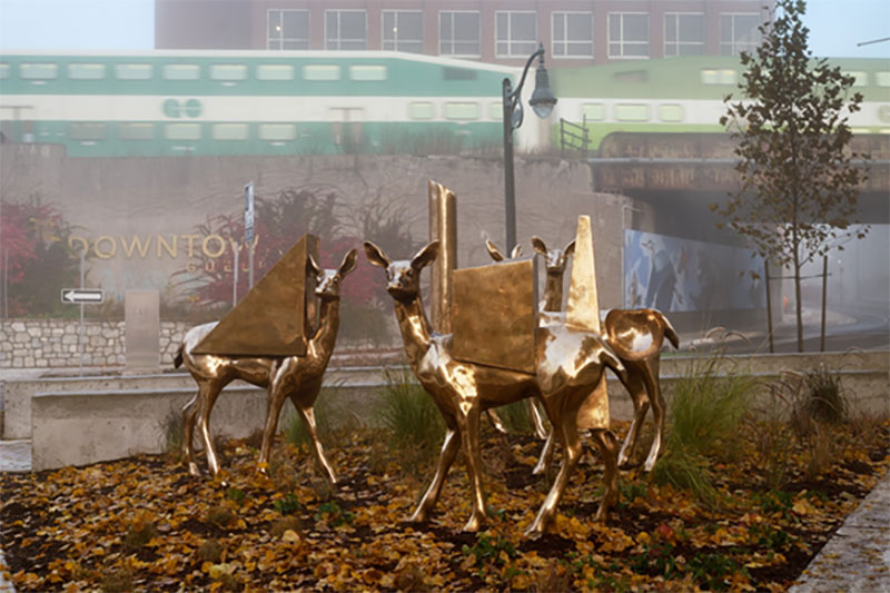 4 statues of deer in front of Downtown Guelph sign